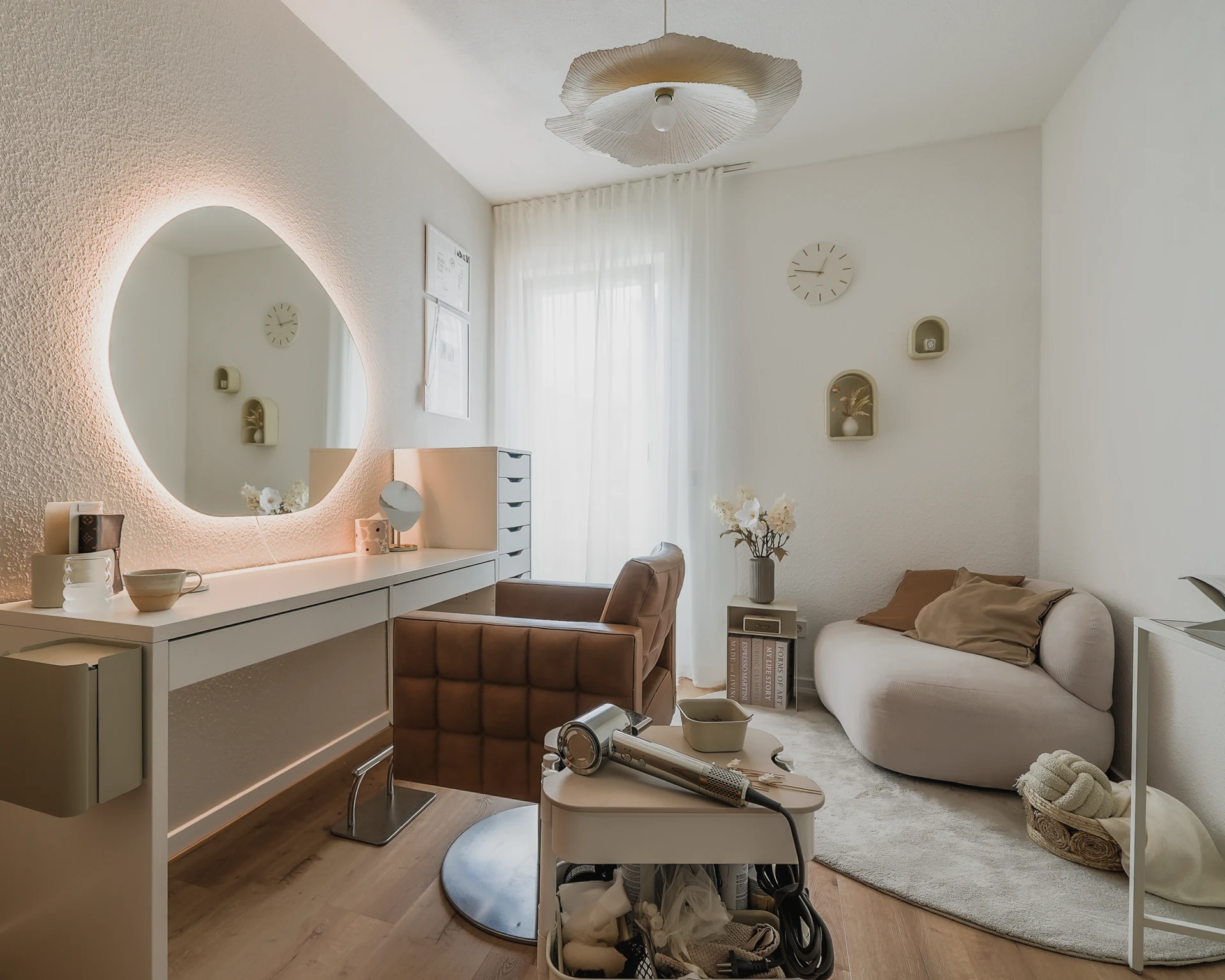 Make-up-Studio mit rundem Spiegel, Stylingplatz und heller Sitzecke.